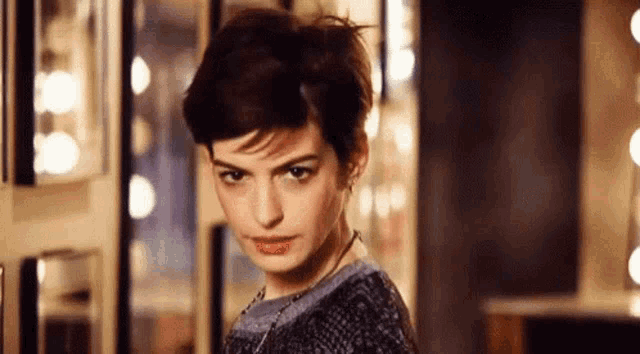 a woman with short hair is looking at the camera .