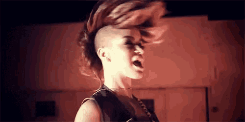 a woman with a mohawk and a shaved head is singing .