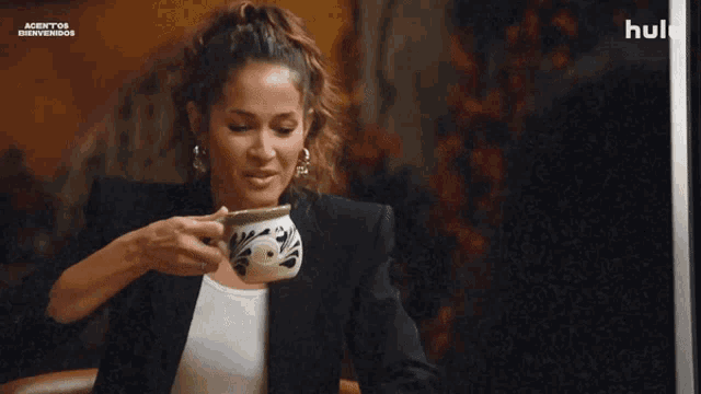 a woman is drinking from a cup with a hulu logo in the background
