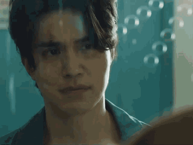 a man with a scar on his face is looking at himself in a mirror