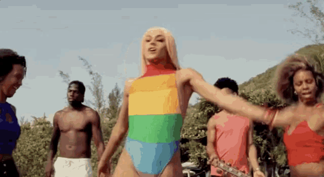 a group of people are standing around a woman in a rainbow swimsuit .