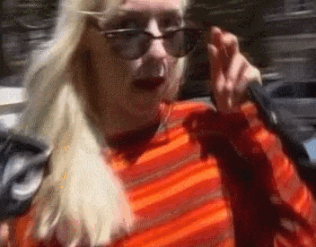 a woman wearing glasses and an orange striped shirt is walking down the street .