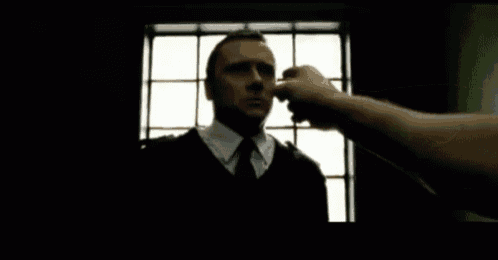 a man in a suit and tie is being punched in the nose by another man .