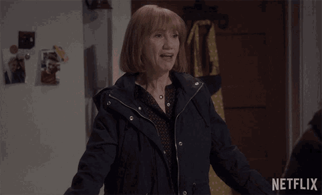 a woman in a blue jacket is standing in front of a door that says netflix on it
