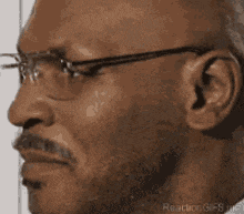 a close up of a man wearing glasses and a beard .
