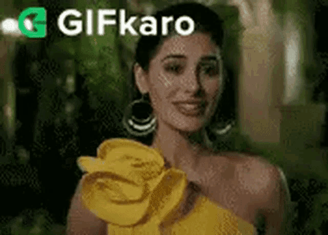 a woman is wearing a yellow dress with a flower on the shoulder .