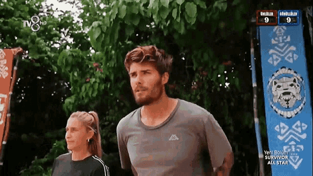 a man and a woman are standing in front of a banner that says " survivor all star "