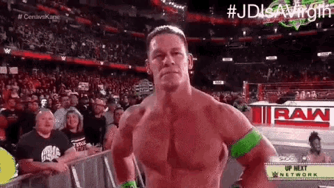 a shirtless wrestler is standing in front of a crowd in a stadium .