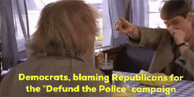 two men are sitting at a table with the words " democrats blaming republicans for the " defund the police " campaign