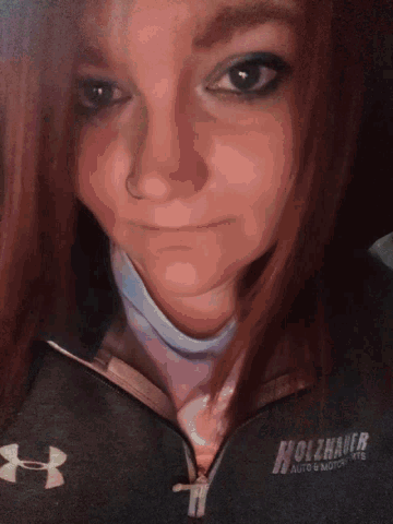a woman wearing a black under armour jacket looks down
