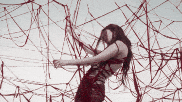 a woman in a red dress is surrounded by red yarn
