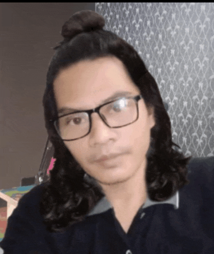 a man with long hair wearing glasses and a top knot