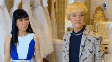 a man and a woman are standing next to each other in a room in front of a mannequin .