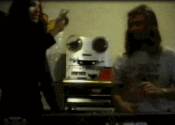 a man and a woman are standing in front of a tape machine
