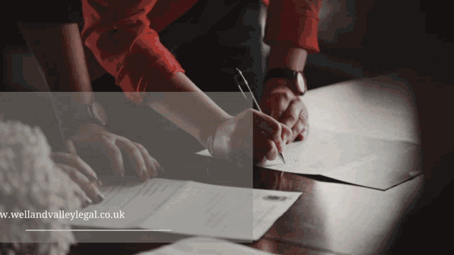 a group of people are signing papers with the website wellandvalleylegal.co.uk in the background