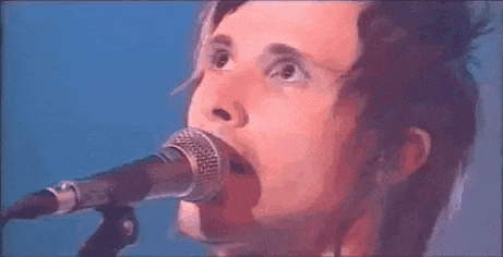 a close up of a man singing into a microphone on a stage .