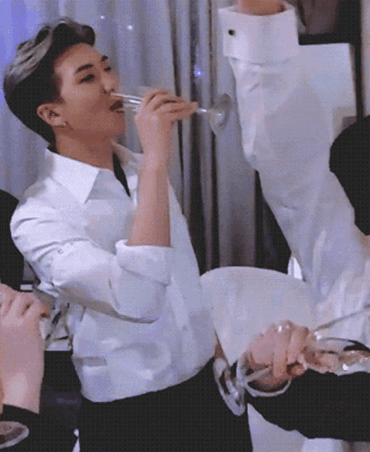 a man in a white shirt drinks from a glass
