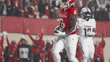 a football player in a red jersey is running with a ball .