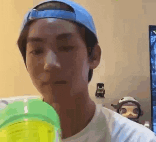 a man wearing a blue hat is holding a green bottle .