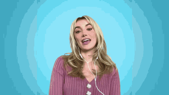 a woman in a pink sweater is wearing ear buds on her neck