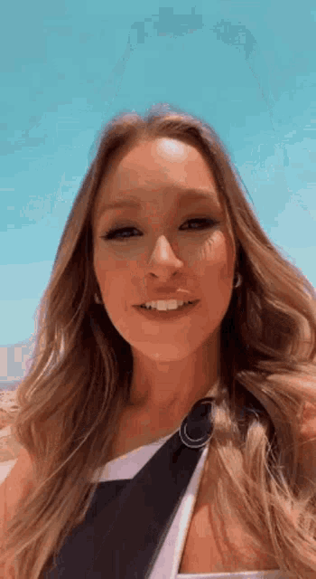 a close up of a woman 's face with a blue sky behind her .
