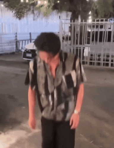 a man in a black and white striped shirt is walking down the street
