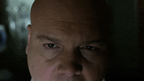 a close up of a bald man 's face with a dark background