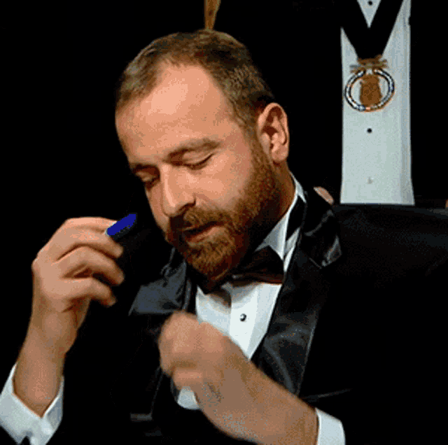 a man in a tuxedo is holding a pen in his hand