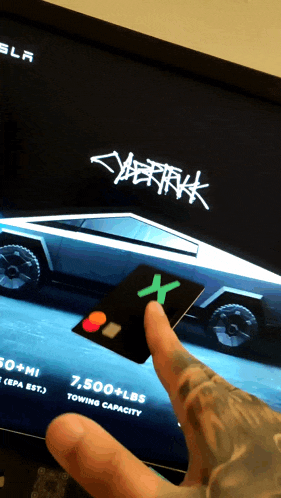 a person is holding a credit card in front of a cybertruck