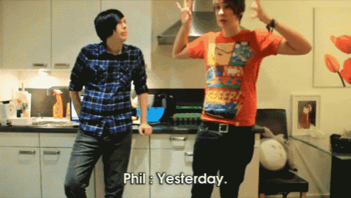 two young men are dancing in a kitchen and one of them is wearing an orange shirt that says yesterday