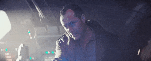a man is standing in a dark room with a blue light coming out of the ceiling .