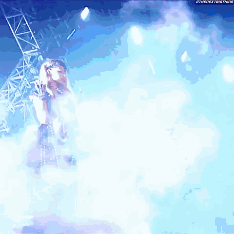 a woman in a black dress is standing in a cloud of smoke on a stage with the next big thing written on the bottom