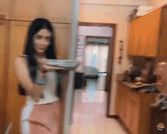 a woman is standing in a kitchen holding a plate in her hand .