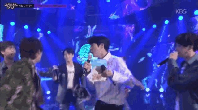 a man holding a microphone on a stage with kbs written on the bottom right