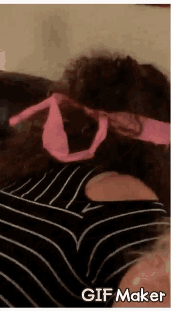 a woman wearing a black and white striped shirt has a pink ribbon tied around her head