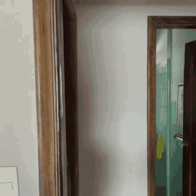 a door with a wooden frame is open to a bathroom with a yellow towel hanging on the wall