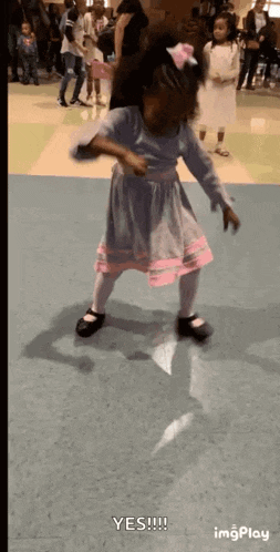 a little girl in a blue and pink dress is dancing in a room .