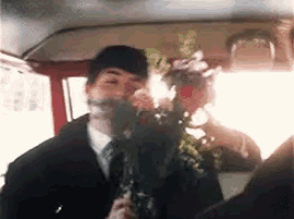 a man in a suit holds a bouquet of flowers in his hand