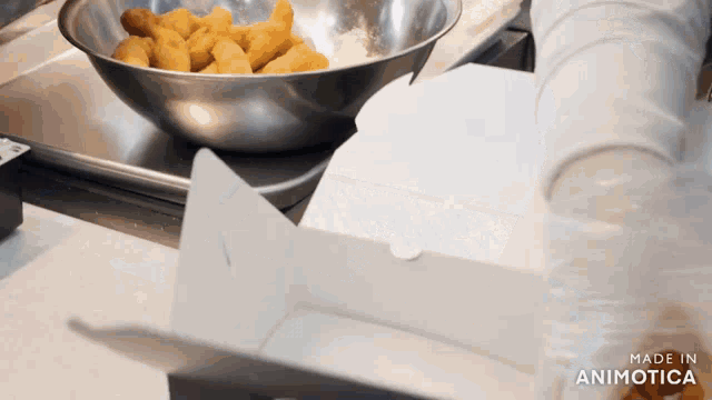 a bowl of chicken nuggets is being taken out of a cardboard box