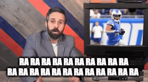 a man with a beard is sitting in front of a television .