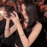 a woman is taking a picture of herself in front of a crowd of people .
