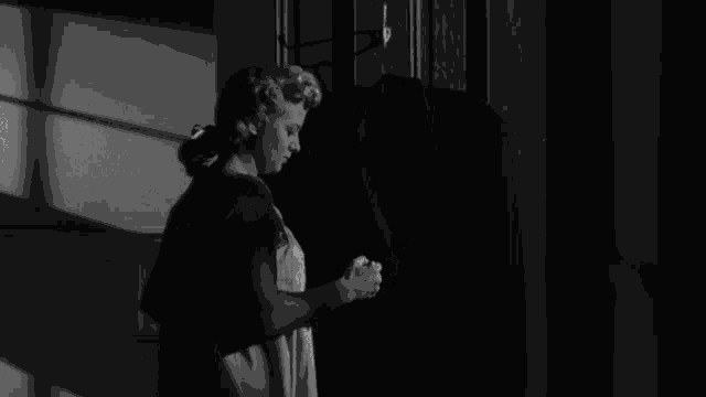 a black and white photo of a woman looking at a coat