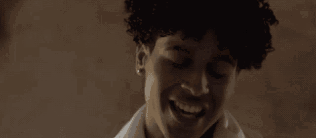 a man with curly hair is making a funny face with his hands in the air