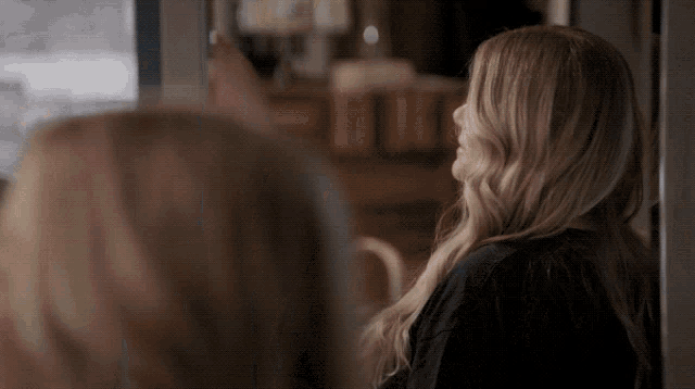 a woman with long blonde hair is standing in a doorway