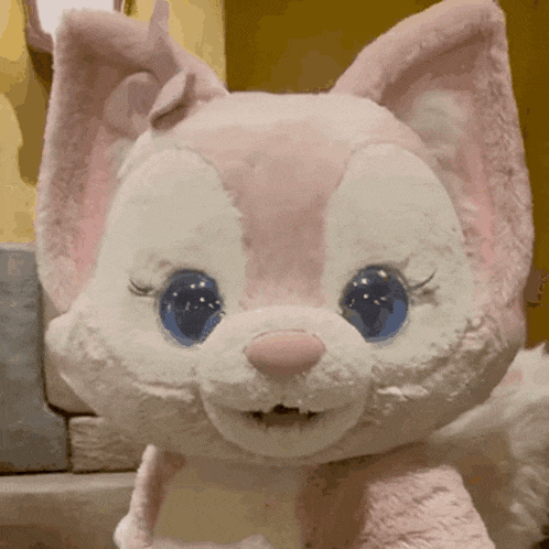 a pink and white stuffed animal with blue eyes