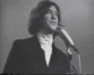 a man in a suit is singing into a microphone in a black and white photo