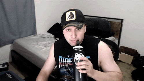 a man wearing a shirt that says ride is drinking from a bottle