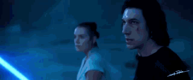 a man and a woman are standing next to each other in a dark room looking at a blue light