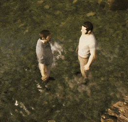 two men are standing in the water and one of them is pointing