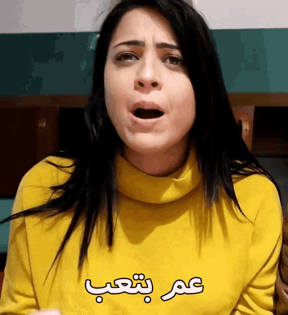 a woman wearing a yellow sweater has arabic writing on her sweater